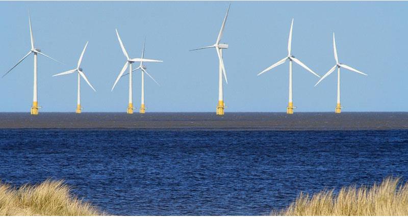 A picture of a row of wind turbines on the shore line