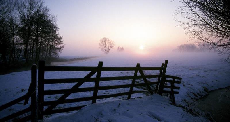 A gate to a field with a light dusting of snow
