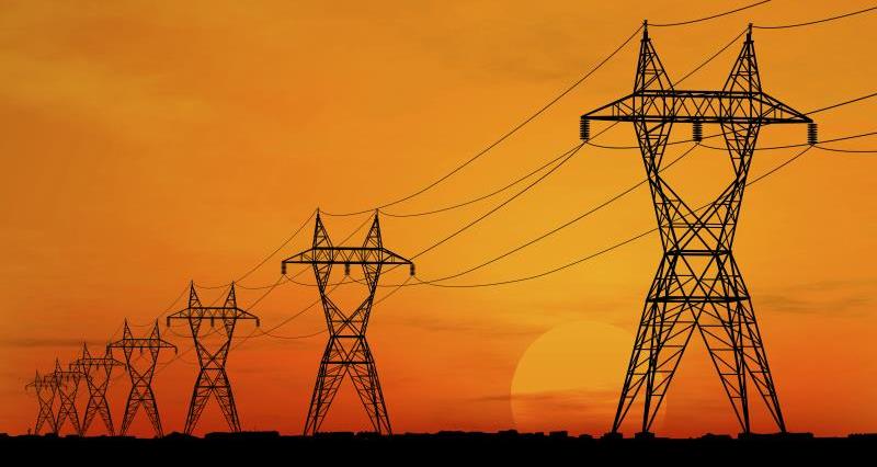 A picture of a row of electricity pylons against a red and yellow sunset