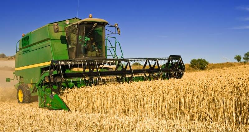 A picture a combine harvester, harvesting crops in a field during the summer