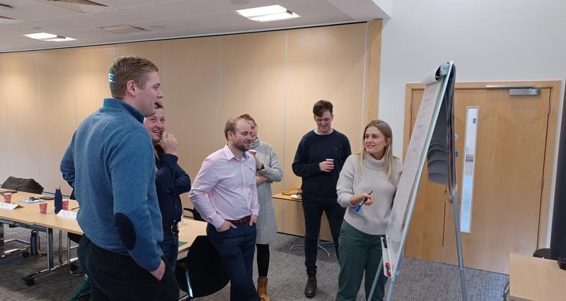 An image of PIP participants stood around a flip chart during the leadership training.