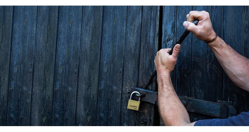 An image of someone breaking a padlock on a door
