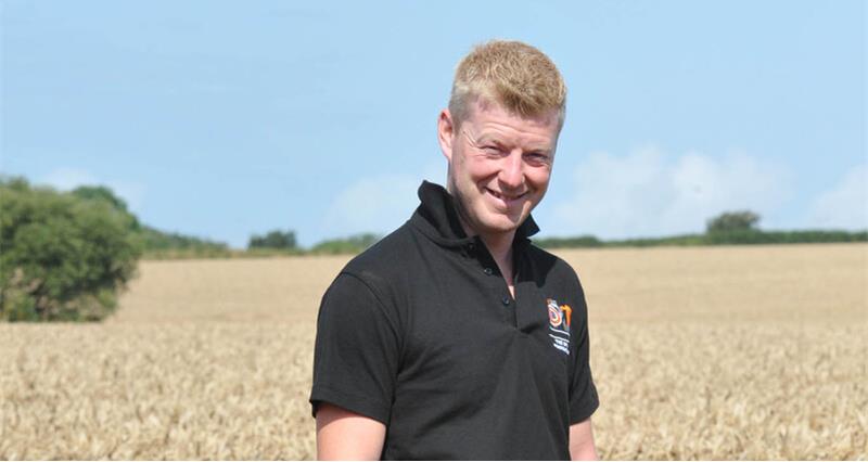 An image of Tom Rees stood in a field of unharvested crops