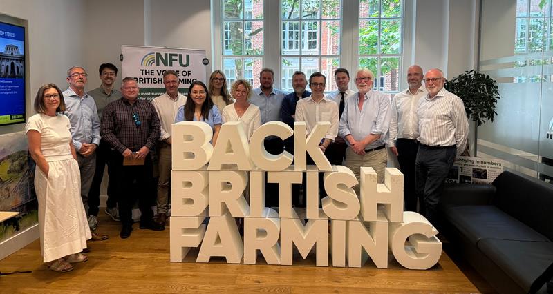 Representatives at the meeting gather together around a “Back British Farming” sign