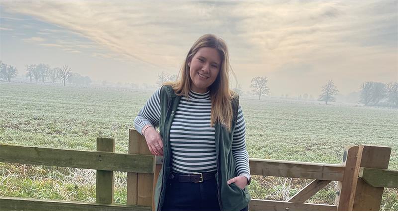 An image of Hannah Cuthbert leaning against a gate