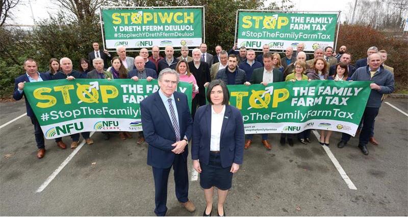 NFU Cymru Council members standing with Stop The Family Farm Tax banners