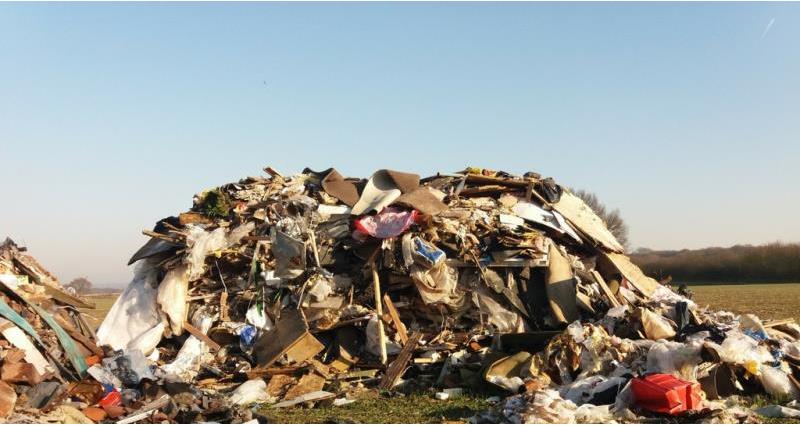 A big pile of rubbish dumped in a field.
