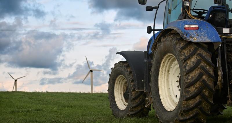An image of a tractor with wind turbines in the background