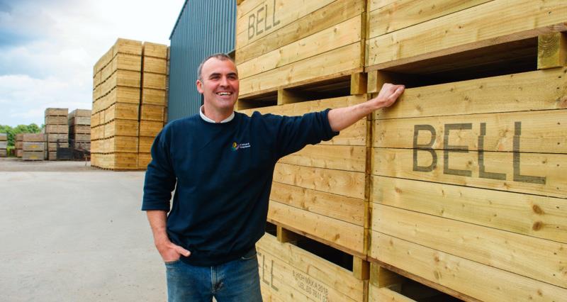 David Bell leaning against wooden pallets