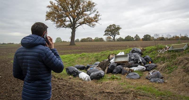 A farmer on his mobile phone reporting fly-tipping on his land