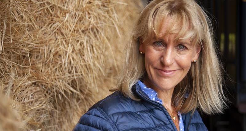 A photo of NFU President Minette Batters posing in front of stacked hay bales