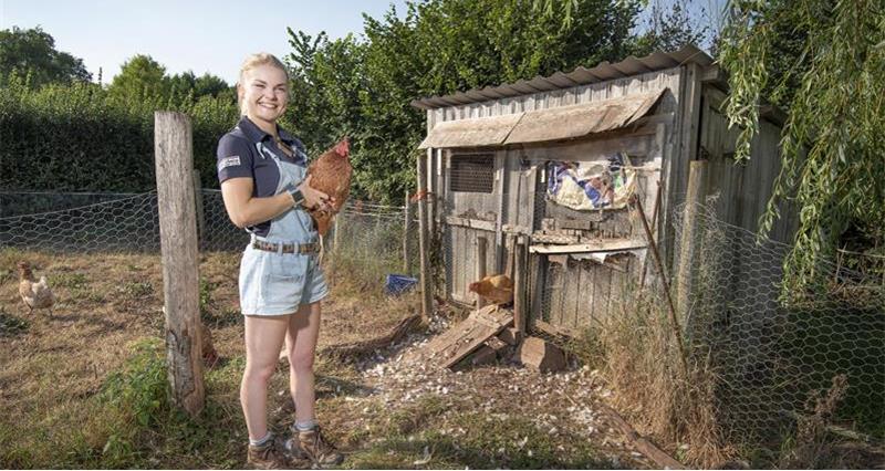 An image of Zoe Legg holding a hen 