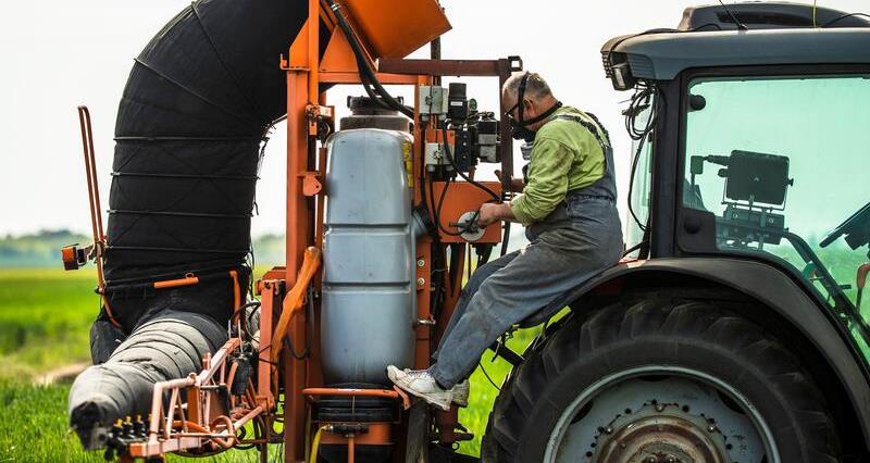 Farmer operating a tractor wearing PPE