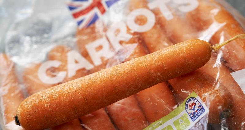 A carrot on top of a bag of Red Tractor assured carrots