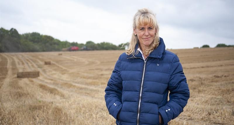 A photo of NFU President Minette Batters. She is standing in a field wearing a blue jacket. 