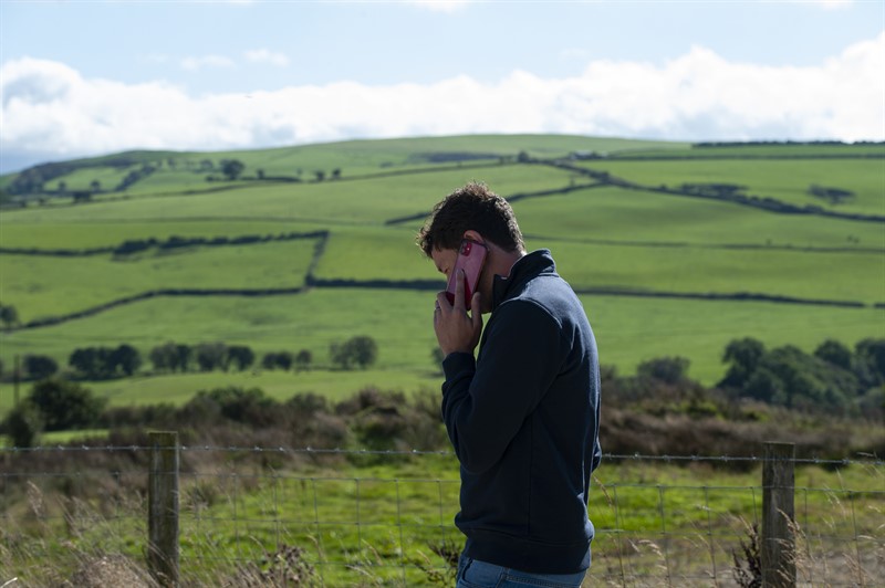A man speaking on a phone in a field