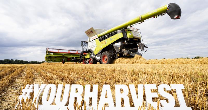 A #YourHarvest sign in front of a combine harvester.