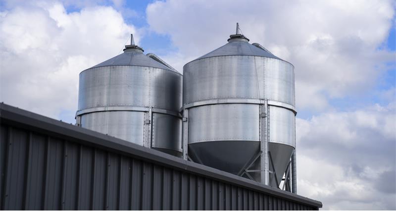 A photo of two large silos above a storehouse. 