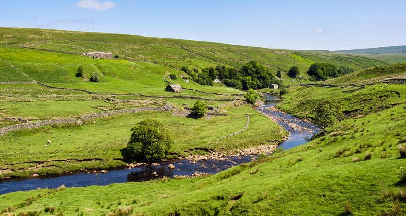 English countryside landscape with barns and a river