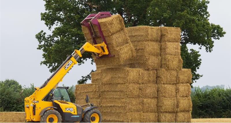 A forklift truck lifting hay bales on a farm