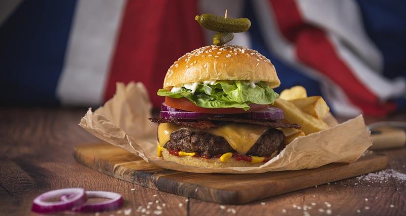 A photo of a beef burger behind a British flag.