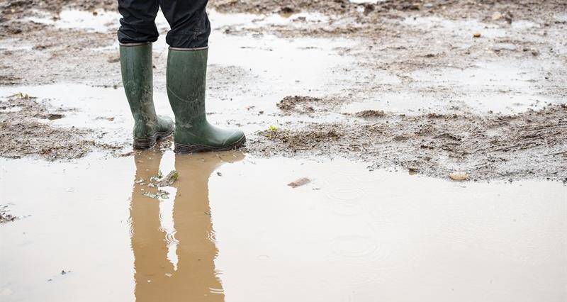 A person wearing wellies stood in a muddy puddle