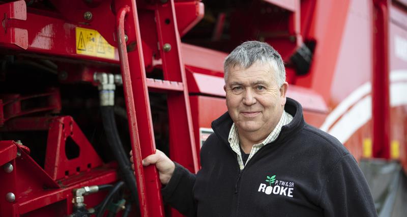A photo of Tim Rooke standing next to a red tractor.