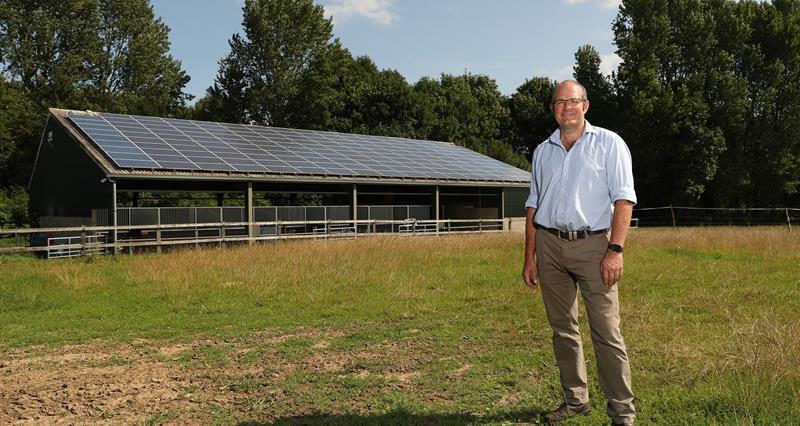 An image of NFU Deputy President Tom Bradshaw stood in front of a solar panel