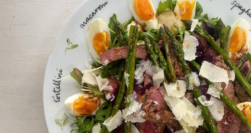 An image of the summery beef salad with beetroot, rocket and eggs, new potatoes and asparagus, served on a white plate. 
