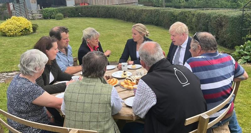 NFU President Minette Batters talks to Prime Minister Boris Johnson at a table on a farm in Devon