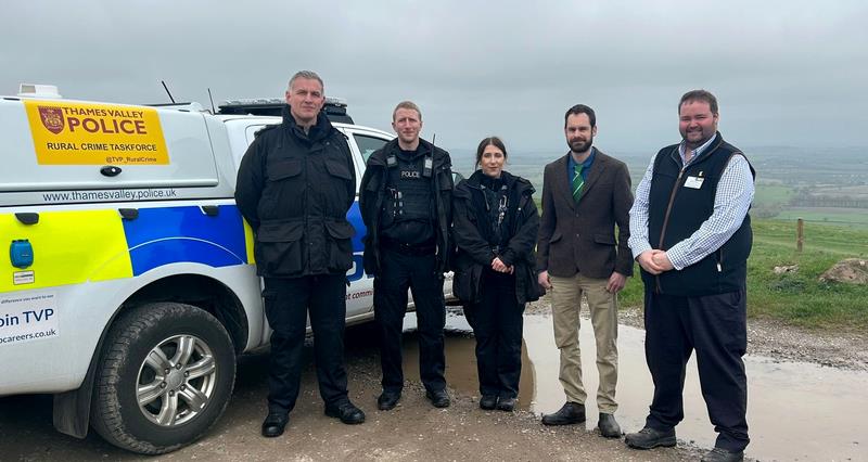 A group of people standing in front of a police vehicle