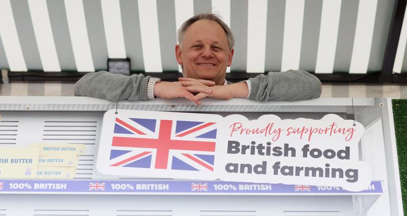 Andrew Blenkiron leaning over a sign which reads 'Proudly supporting British food and farming'