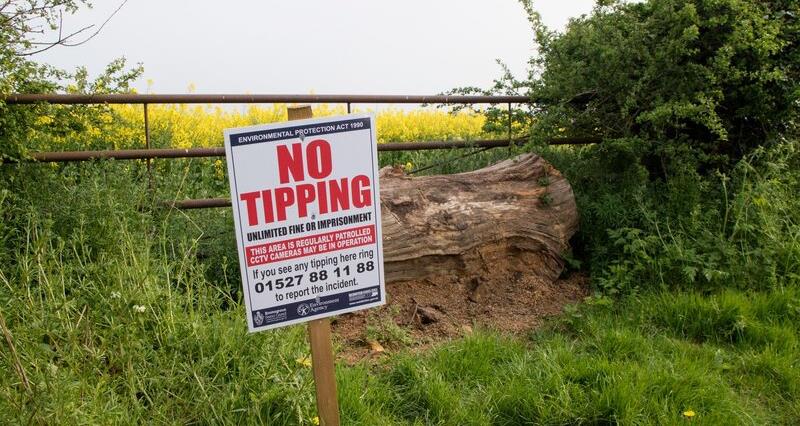 A fly tipping sign in front of a farm gate