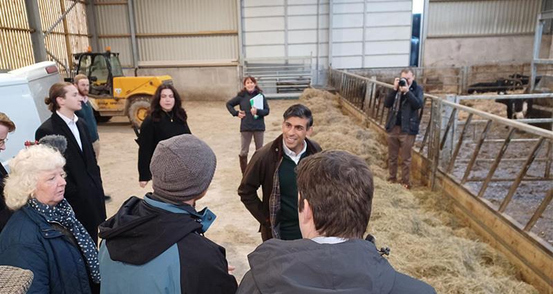 Rishi Sunak talking to a crowd of farmers inside a farm shed