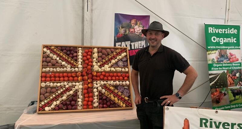 Simon Bennett in a tent stood next to a union jack comprised of food