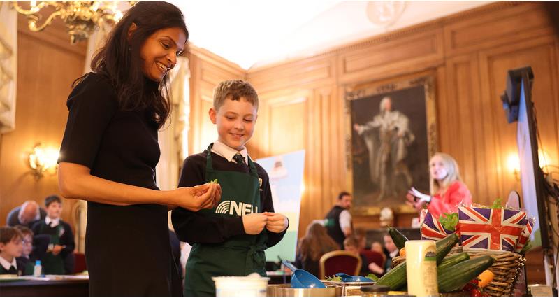 Akshata Murty with a young boy wearing an NFU apron looking at a table of food