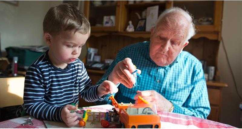 Grandad and grandson playing with toy tractor