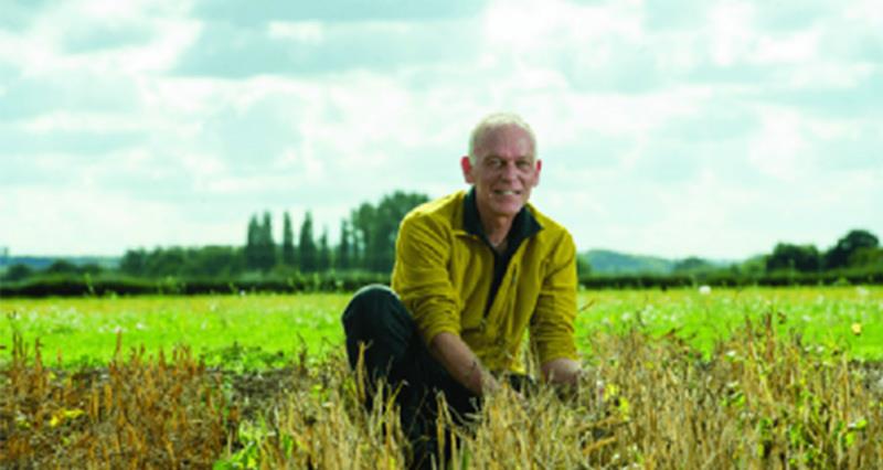 Professor Eric Holub kneeling in a field