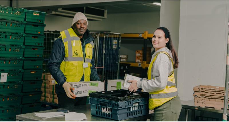 Two workers at FareShare handling food donations