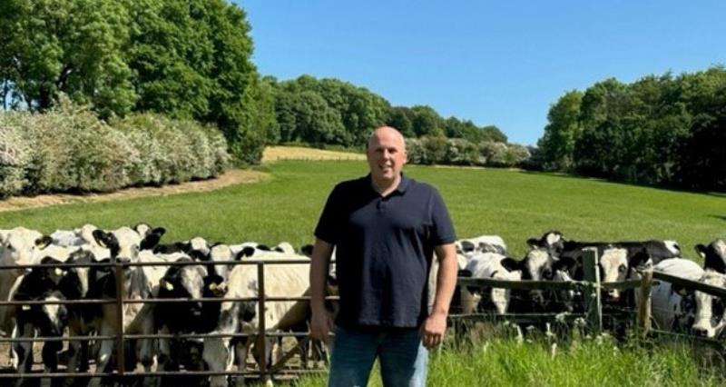 A photo of the Chris Pearson on his farm, in front of a herd of his cows.