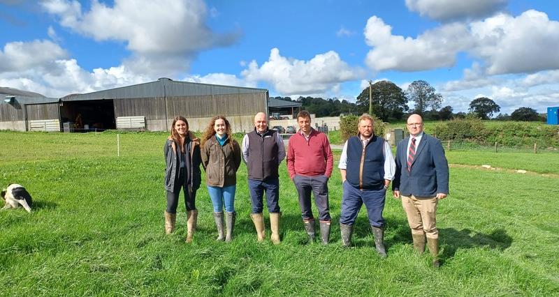 A photo of the NFU livestock team on farm in Ireland. They are standing on a field wearing wellies. In the background is a storehouse. 