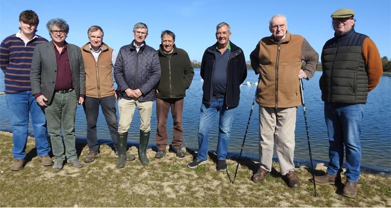 Farmers standing in front on a few farmland reservoir filled with water