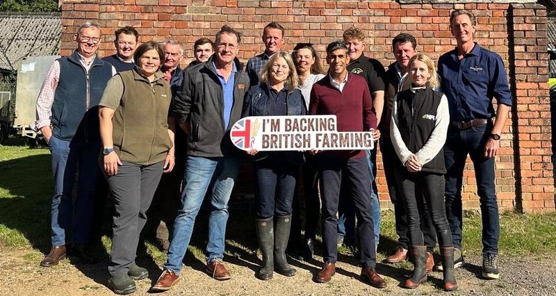 Rishi Sunak standig outside a farm building with NFU members in Surrey