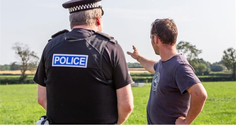 A police officer talking to a farmer, with their backs to camera