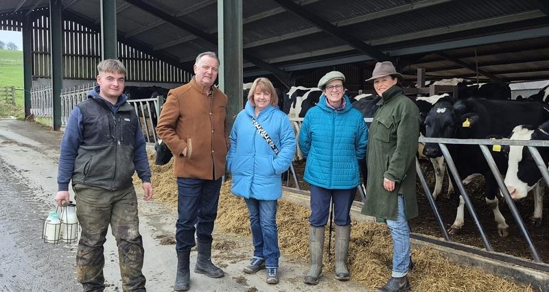 Paul Marshall and farmers standing outside an open barn, with cattle on the right