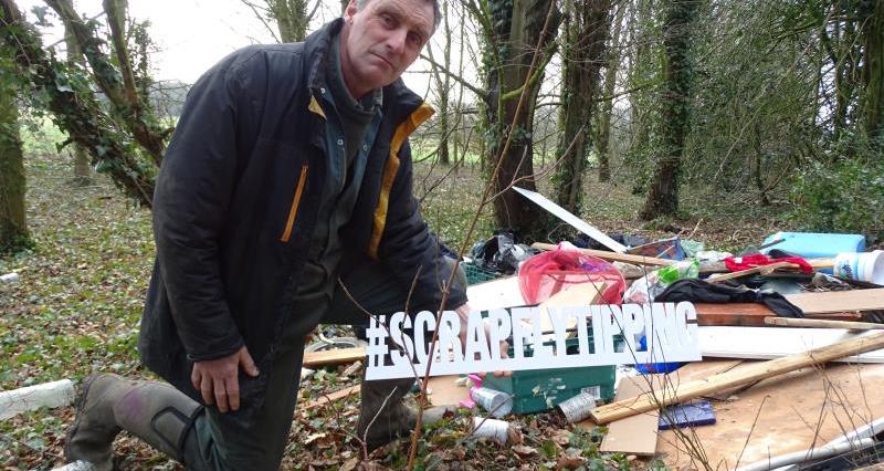 Farmer Will Dickinson in front of fly tipped waste