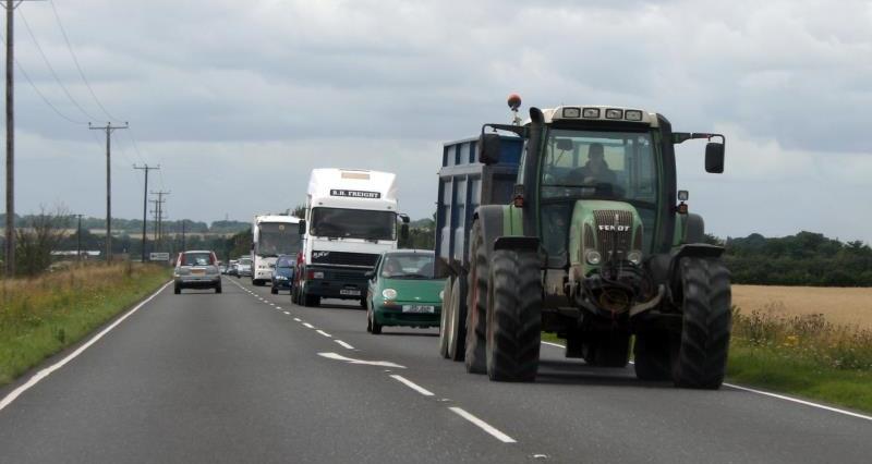 An image of a tractor driving down a busy road