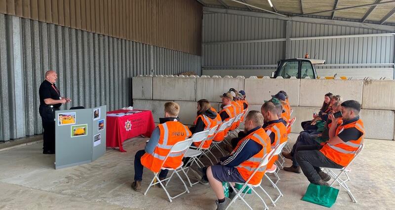 Farmers in a barn listening to a fire safety briefing