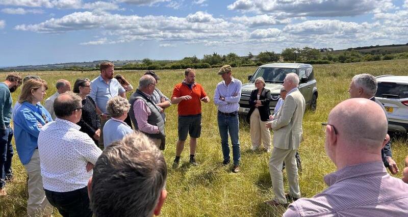 A photo of Farming Minister speaking to members in a field on farm