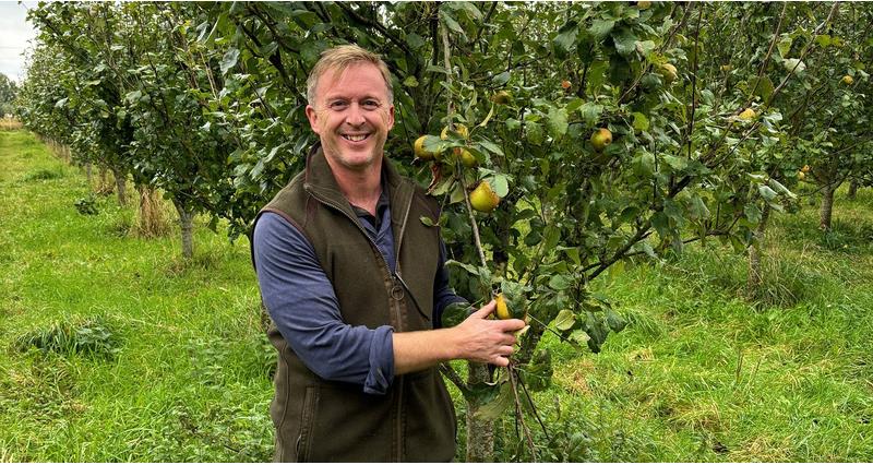 NFU member Jonny Hewitt stood with his apple trees on farm